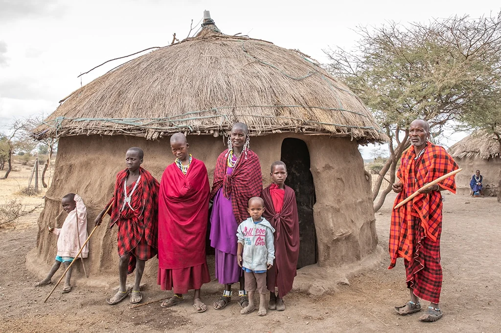 A Maasai family in front of their enkajijik at Mikumi National Park Tanzania